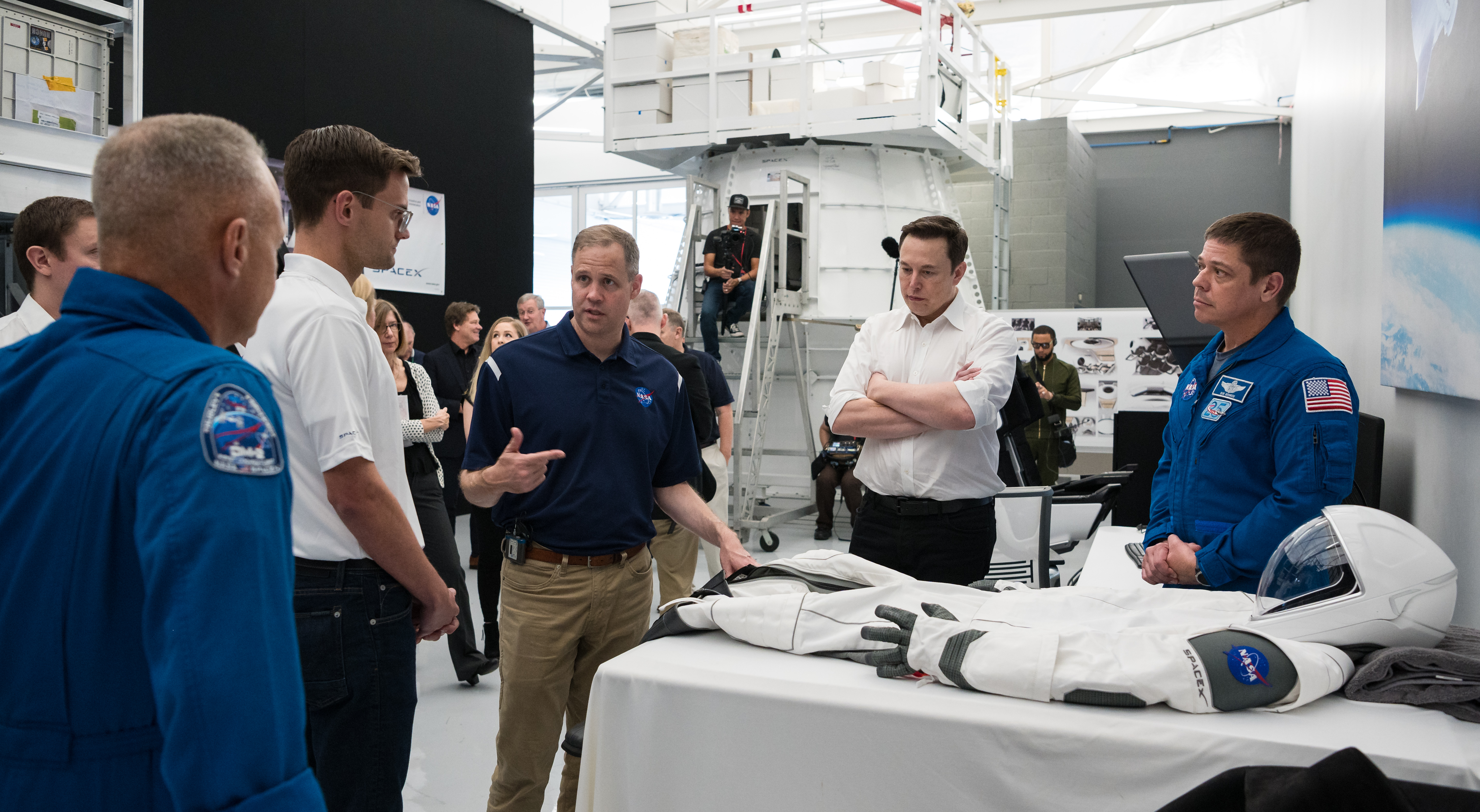 Jim Bridenstine wraz z Elonem Muskiem oraz astronautą Bobem Behnkenem, patrzący na skafander SpaceX, identyczny do tego który będzie wykorzystany podczas misji Crew Demo-2 (Źródło: NASA/Aubrey Gemignani)